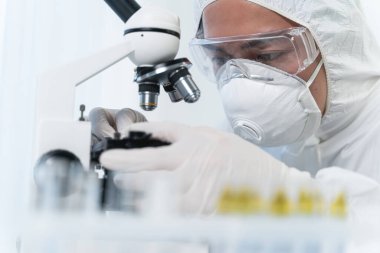 Attentive international scientist working with his microscope