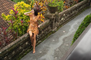 Genç ve güzel kadın tropik bitkilerin tadını çıkarıyor.