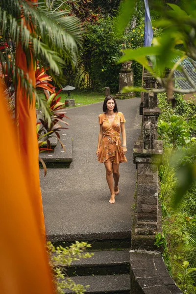 Mulher morena atraente andando e olhando para palmas — Fotografia de Stock