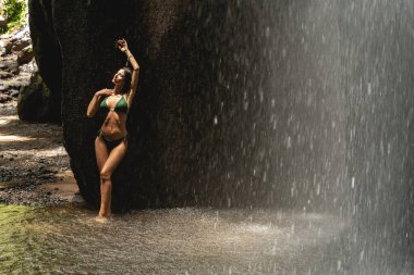 Beautiful brunette female leaning on the rock