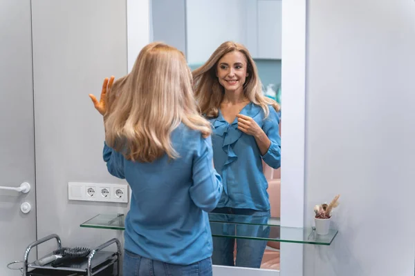 Positive delighted young blonde looking at her reflection — Stockfoto