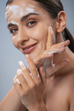 Beautiful lady washing her face with hands by soap