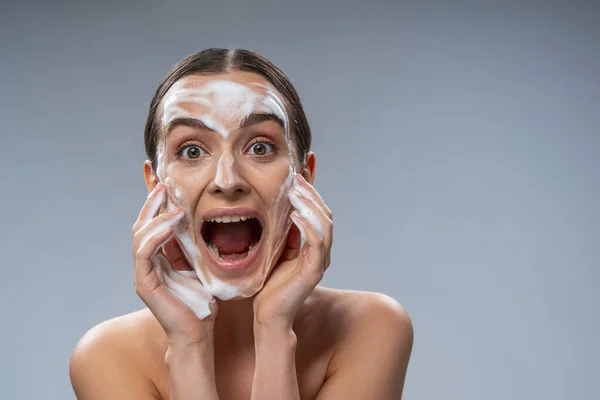 Young beautiful lady washing her face with soap — Stok fotoğraf