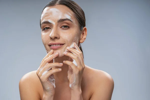Senyum wanita cantik mencuci wajahnya dengan sabun — Stok Foto