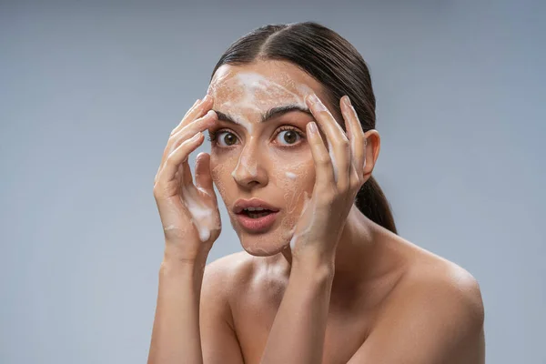 Молода приваблива дама миє обличчя з милом — стокове фото