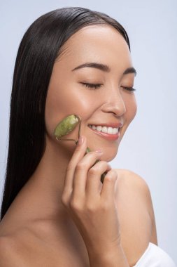 Asian girl using natural massager tool in studio