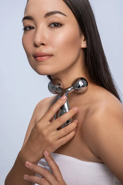 Pretty woman is using facial roller in studio — Stockfoto