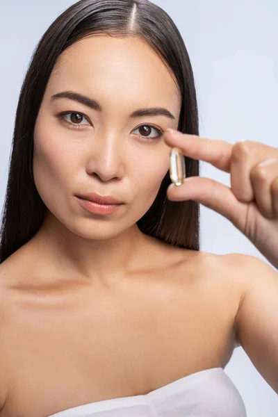 Bella asiatico femmina mostrando pillola con omega 3 — Foto Stock