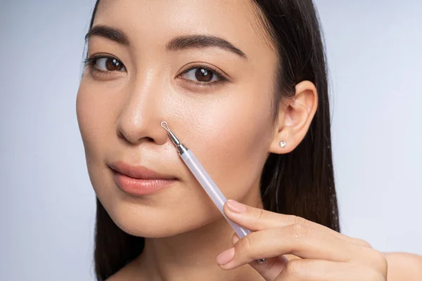 Bastante mujer asiática está apretando el acné en el interior — Foto de Stock