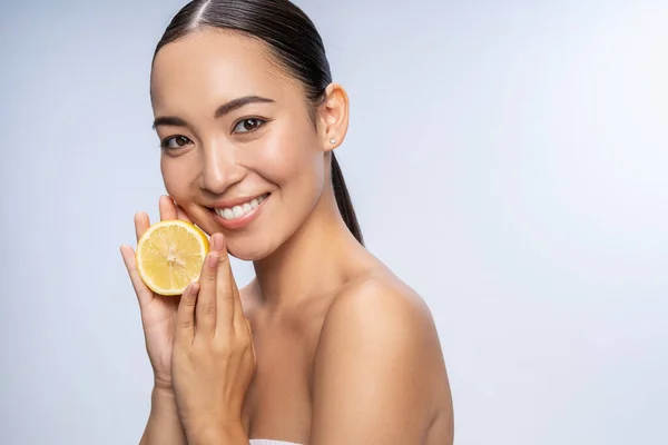 Šťastná mladá žena ukazuje čerstvý citron ve studiu — Stock fotografie