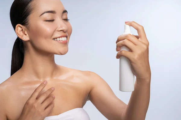 Sorrindo senhora asiática está aplicando água termal — Fotografia de Stock