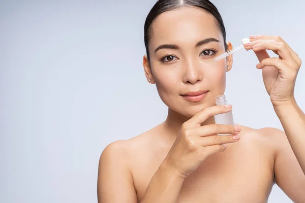 Retrato de una joven sosteniendo un elixir cosmético — Foto de Stock