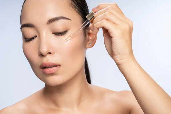 Азиатская красивая женщина применяет глазную сыворотку — стоковое фото