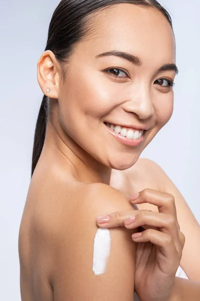 Happy pretty female applying lotion on hand — Stock Photo, Image