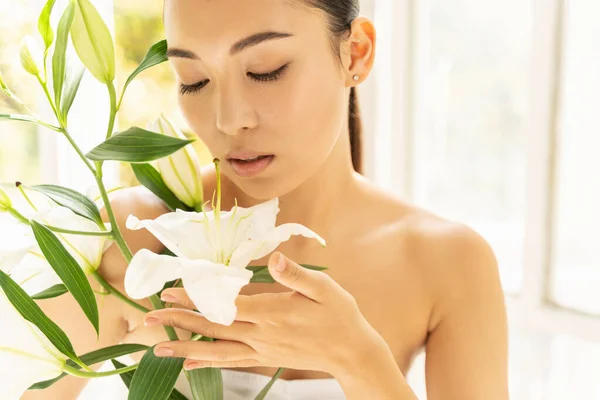 Beautiful Asian lady with flowers in room — Stock Photo, Image