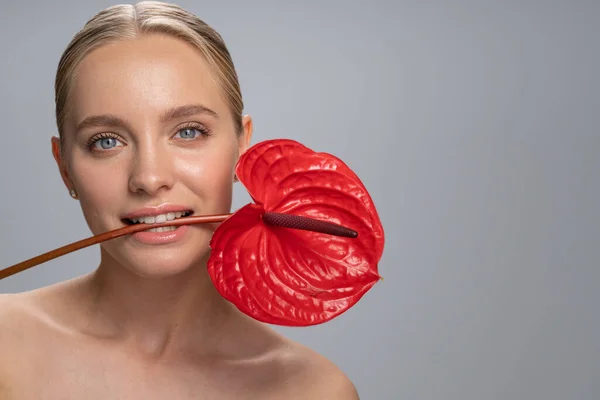 Persona femenina encantada positiva manteniendo la flor en los dientes — Foto de Stock
