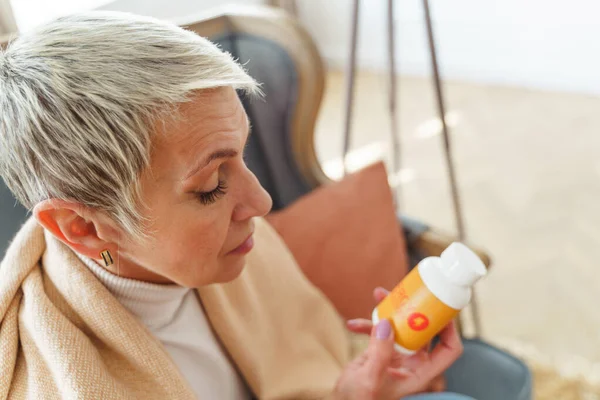Ηλικιωμένη κυρία κοιτάζει ένα μπουκάλι — Φωτογραφία Αρχείου