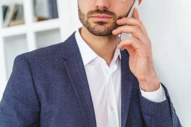 Sakallı beyaz adam telefon görüşmesi yapıyor.