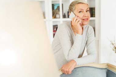 Tarz sahibi beyaz bir kadın telefon görüşmesi yapıyor.