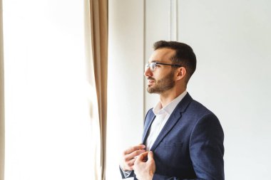 Ciddi bir stil sahibi iş adamı ofiste duruyor.