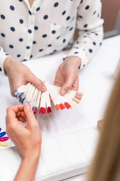 Photo concentrée sur les mains féminines qui choisissent le vernis rouge — Photo