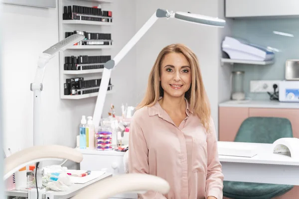 Positive delighted blonde woman sitting in salon — Stock Photo, Image