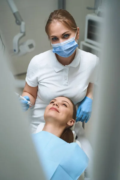 Bayan dişçi stok fotoğrafında bir hastaya bakıyor. — Stok fotoğraf