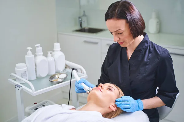 Attentive cosmetologist looking at her pretty client — Stock Photo, Image