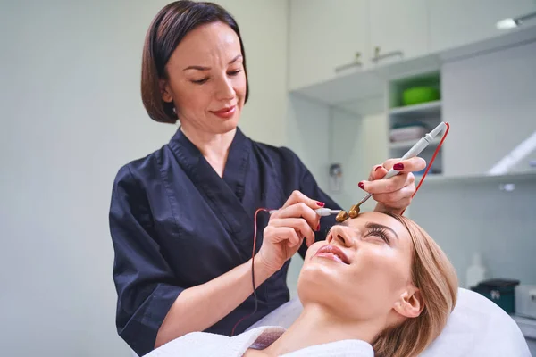 Pozorný brunetka kosmetolog pomocí speciální sterilní zařízení — Stock fotografie