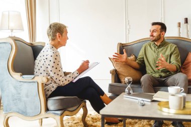 Neşeli erkek hasta psikoloğuyla iletişim kuruyor.