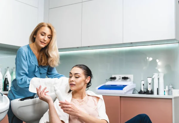 Duas jovens mulheres discutindo cosméticos profissionais para o cabelo — Fotografia de Stock