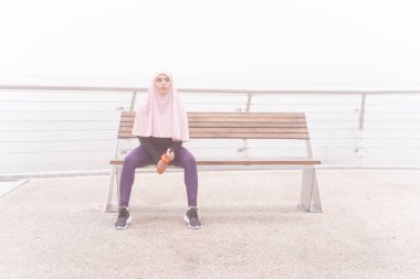 Bir şişe su deposu fotoğrafıyla çekici, yorgun bir sporcu kadın.