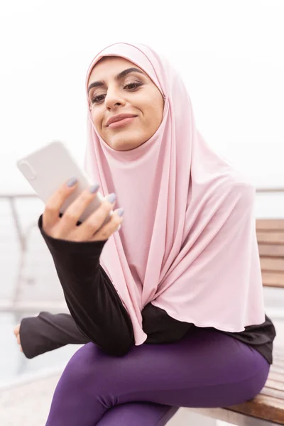 Mulher muçulmana sorridente com foto stock smartphone — Fotografia de Stock