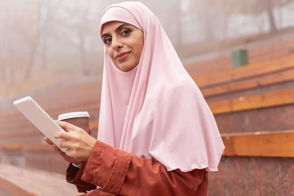 Senhora atraente em hijab sagacidade café e gadget fotos stock — Fotografia de Stock