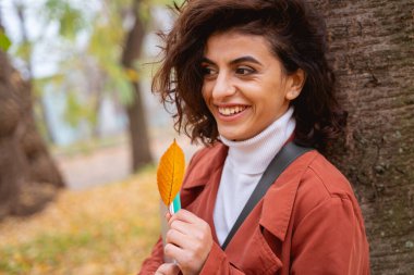 Ağaç kabuğu fotoğrafının yanında gülümseyen güzel bayan.
