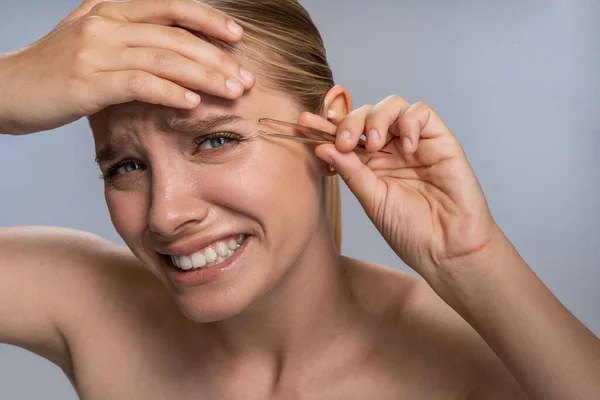 Emotional blonde female person doing eyebrows correction — Stock Photo, Image