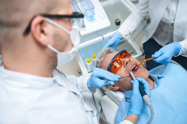 Homem tratado pelo dentista e enfermeira foto stock — Fotografia de Stock