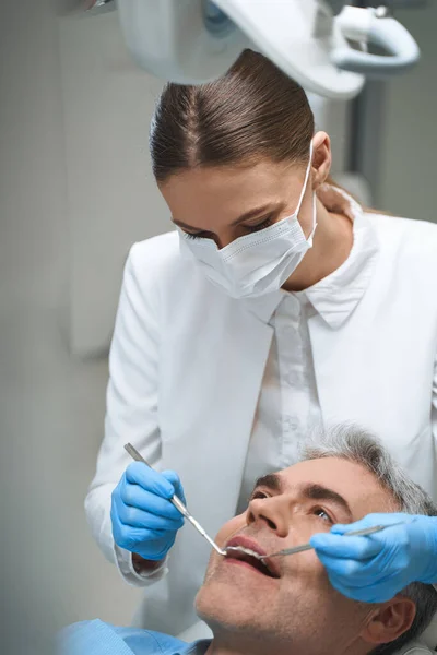 Dentista feminino está tratando homem foto stock — Fotografia de Stock