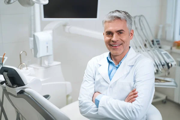 Vrolijke tandarts in zijn kantoor stock foto — Stockfoto