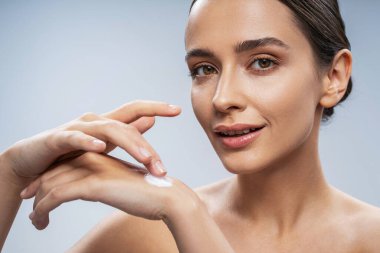 Neşeli kız vücut ve yüz için kozmetik kullanıyor.