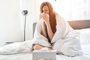 Hasta kız yatakta bacak bacak üstüne atarak oturuyor.