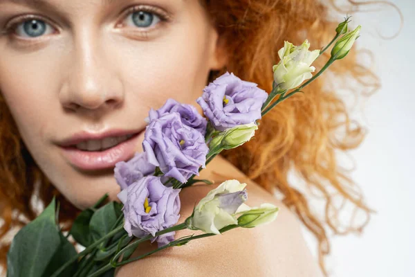 Gelukkig krullend rood vrouw met lila bloemen — Stockfoto