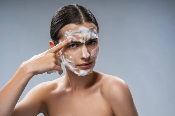 Vtipná mladá žena mytí obličeje s pěnou — Stock fotografie