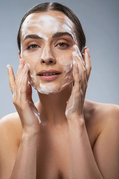 Wanita muda yang ceria mencuci wajahnya dengan sabun — Stok Foto