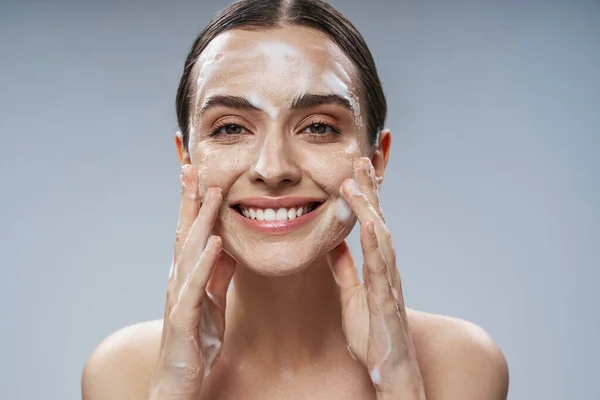 Mujer joven feliz con espuma en la cara —  Fotos de Stock