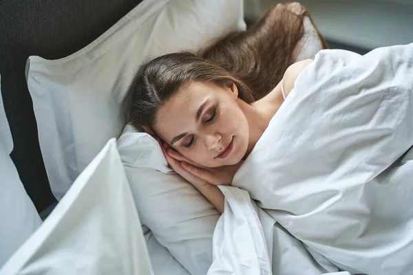 Good-looking young female lying in a bedroom — Stock Photo, Image