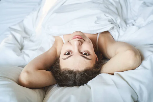 Zâmbind frumos femeie tânără în pat uitându-se în sus — Fotografie, imagine de stoc