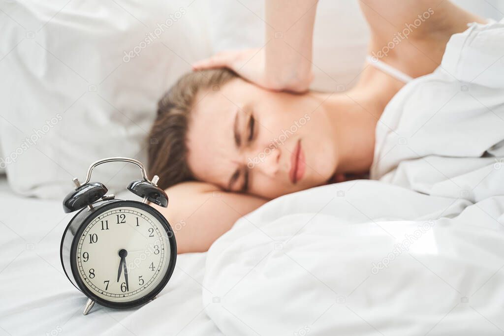 Woman and a ringing twin bell classic alarm clock