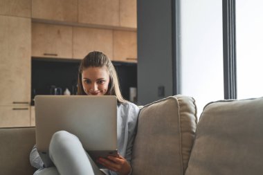 İçerde bilgisayarını kullanan neşeli genç bir kadın.