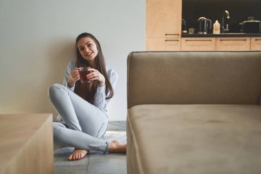 Sıcak bir içeceği olan neşeli genç bir kadın.